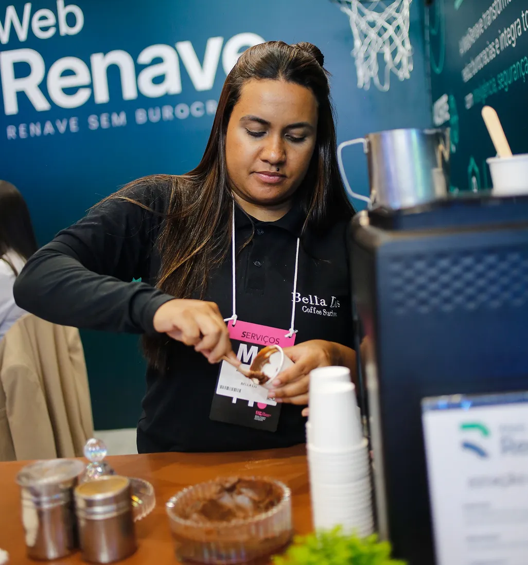 Barista da Bella Lis preparando bebida em estação de café de feira corporativa