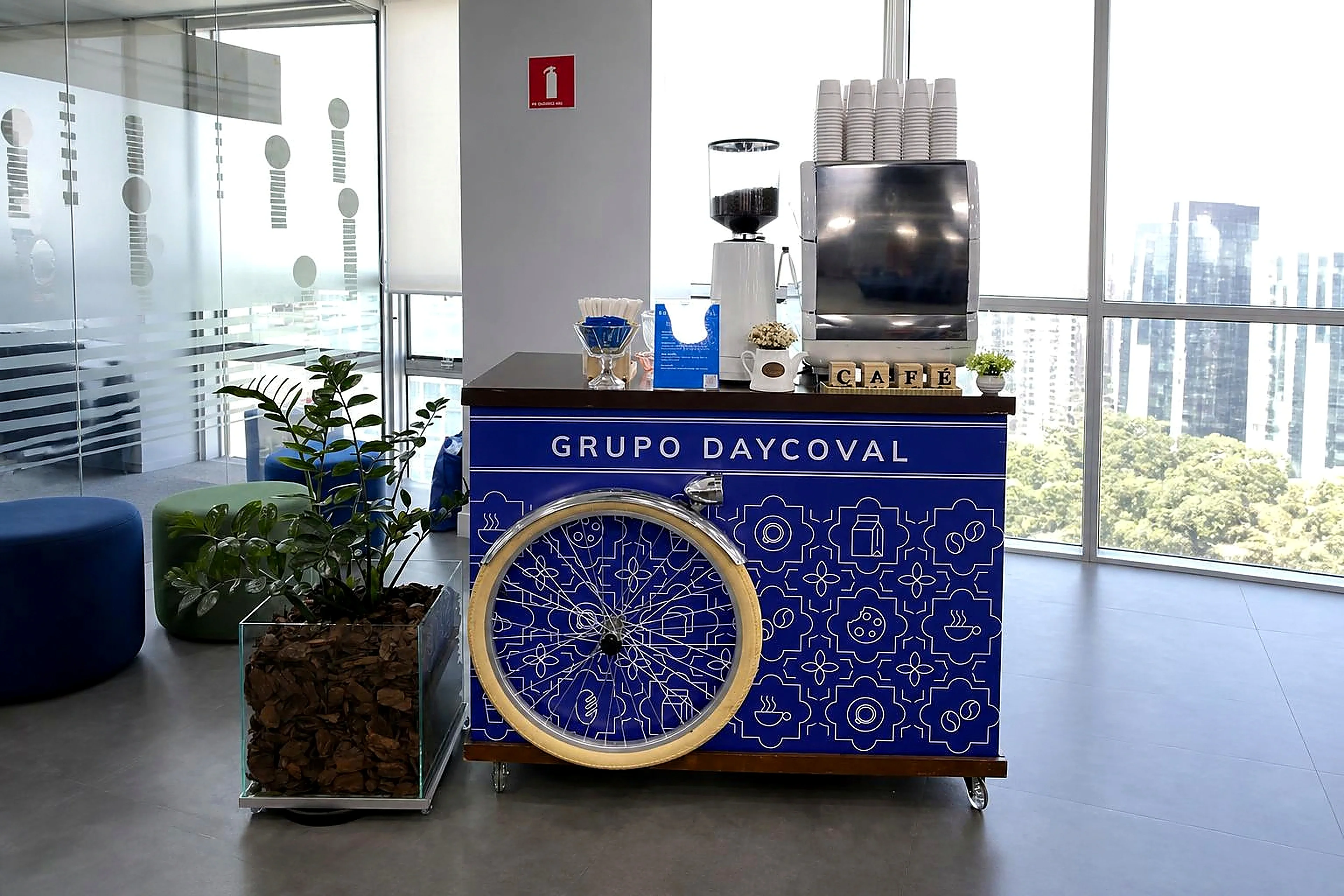 Estação de café da Bella Lis com carrinho personalizado com a identidade visual do Grupo Daycoval em evento corporativo